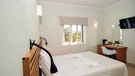 Ett hotellrum med en säng, fönster, skrivbord, stol och TV. (AI-genererad text)