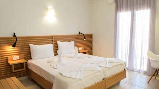 Två sängar med vit sängklädsel, ett trähuvudgavel och dekorativa handdukar formade som svanar. (AI-genererad text)