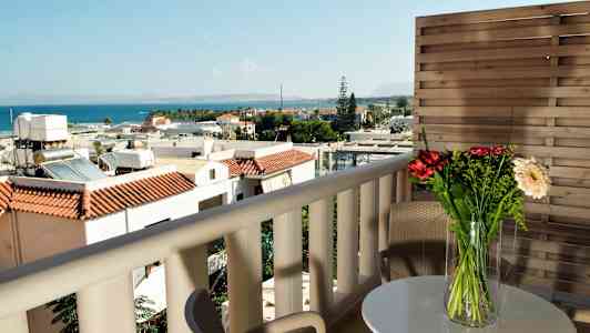 Utsikt från balkong med möbler, blommor på bordet, och havet i bakgrunden. (AI-genererad text)