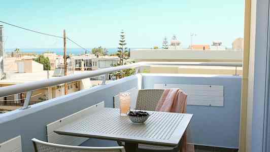 En balkong med utsikt mot havet, med ett bord med körsbär och en dryck. (AI-genererad text)