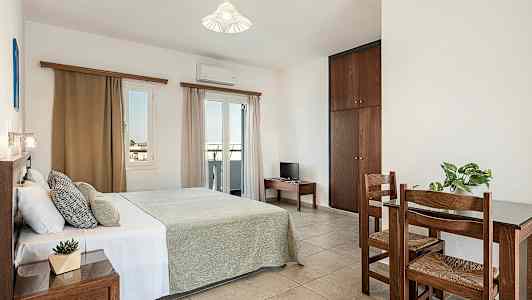 Ett sovrum med en dubbelsäng, ett litet bord med två stolar och en garderob. (AI-genererad text)