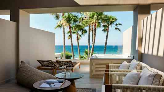 Utomhusområde med sittmöbler, bord och jacuzzi med havsutsikt. (AI-genererad text)