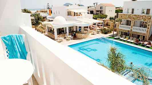 Utsikt från en balkong över en pool och hotellbyggnader. (AI-genererad text)