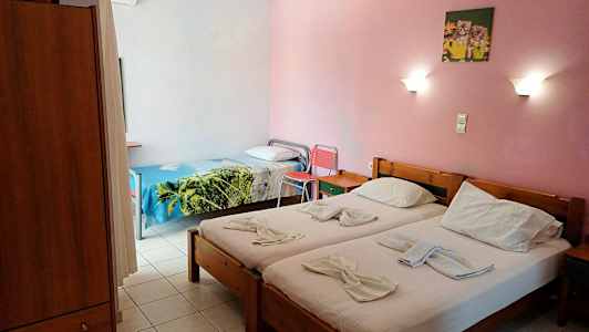 Bild på ett hotellrum med två enkelbäddar och en enkelsäng, rosa väggar och vägglampor. (AI-genererad text)