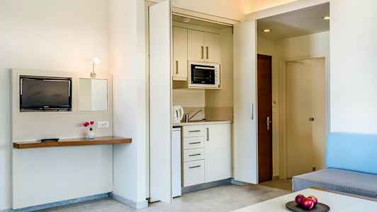 En hotellrum med en liten köksdel och vardagsrumsinredning. (AI-genererad text)