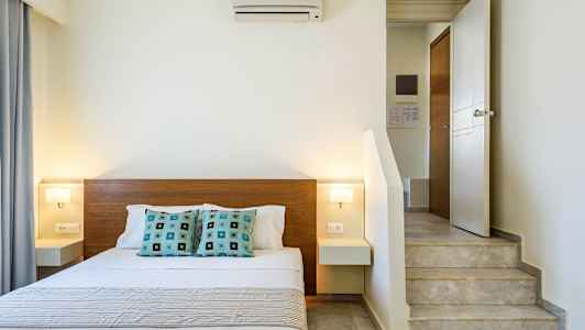 Inomhusbild av ett sovrum med en dubbelsäng, modern inredning och en trappa nära sängen. (AI-genererad text)