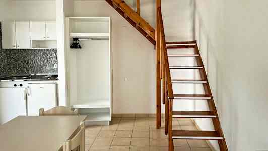 Inomhusbild med ett litet kök, en garderob och en trätrappa till ett loft. (AI-genererad text)