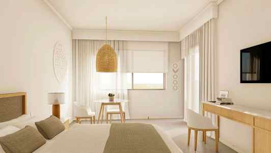 Ett ljust hotellrum med en stor säng, en hängande lampskärm, ett bord med två stolar och en väggmonterad TV. (AI-genererad text)