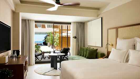 Hotellrum med modern inredning, en dubbelsäng, soffgrupp och stora glasdörrar som leder ut till en terrass. (AI-genererad text)