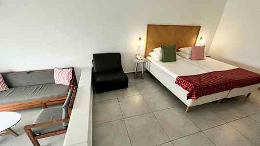 Ett hotellrum med säng, fåtölj och sittmöbel. (AI-genererad text)