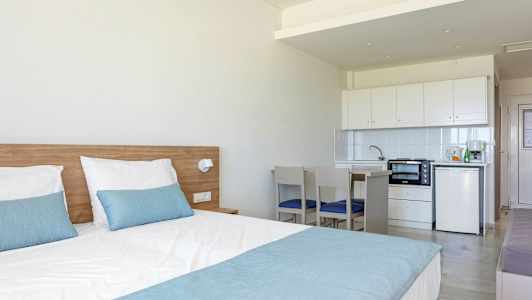 Ett hotellrum med en säng och en liten köksavdelning. (AI-genererad text)