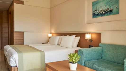 Ett hotellrum med en dubbelsäng, grön soffa och väggkonst. (AI-genererad text)