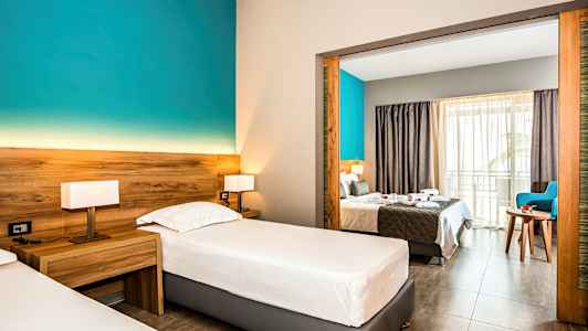 Hotellrum med två enkelsängar och visning mot dubbelrum genom en öppen portal. (AI-genererad text)