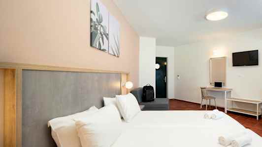 Hotelrum med dubbelsäng, sittplats, skrivbord och TV. (AI-genererad text)