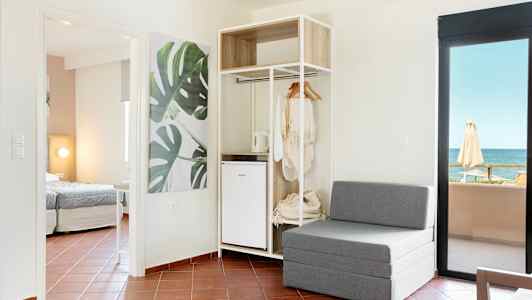 Modernt hotellrum med sittmöbler, öppet klädskåp och havsutsikt. (AI-genererad text)