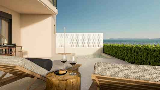 Bild av en terrass med solstolar, ett bord med vinglas och utsikt över havet. (AI-genererad text)