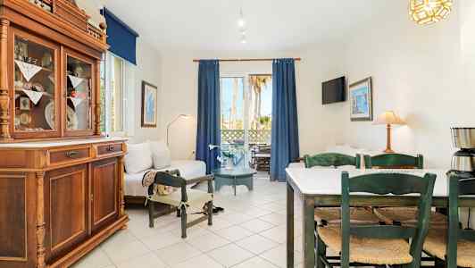 Ett ljust vardagsrum med soffor, matbord och stolar samt stora fönster med blå gardiner. (AI-genererad text)