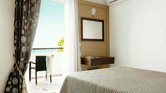 Hotellrum med säng, spegel, gardiner och balkong med utsikt mot havet. (AI-genererad text)