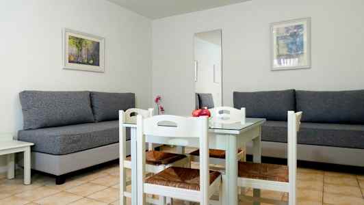 Ett rum med två grå soffor, ett vitt matbord och fyra stolar. (AI-genererad text)