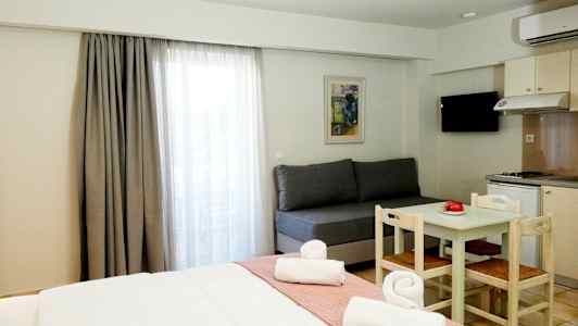 Ett hotellrum med en säng, en soffa, ett matbord med stolar och ett pentry. (AI-genererad text)