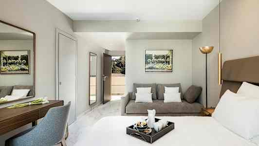 Ett hotellrum med en säng, en soffa och ett skrivbord. (AI-genererad text)