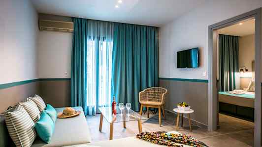 Bild av ett hotellrum med soffa, bord och stol, samt säng i ett separat sovrum. (AI-genererad text)