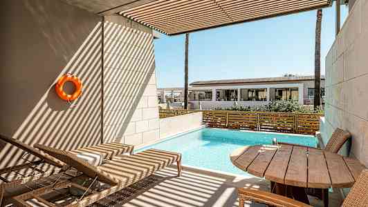 En privat terrass med utsikt över en liten pool, solstolar och ett bord med stolar. (AI-genererad text)