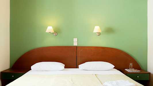 En säng med två sänglampor på en grön vägg. (AI-genererad text)