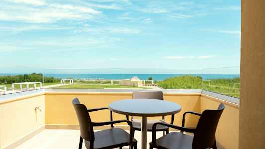 Balkong med bord och stolar med utsikt över havet. (AI-genererad text)