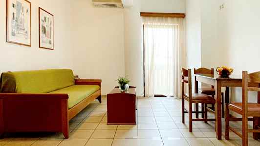 Ett vardagsrum med soffa, soffbord och matbord med stolar. Ljusa väggar och gardiner. (AI-genererad text)