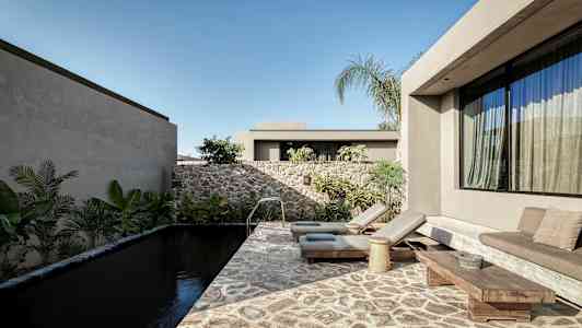 Ett modernt utomhusområde med en stenpool, solstolar och växter omkring. (AI-genererad text)