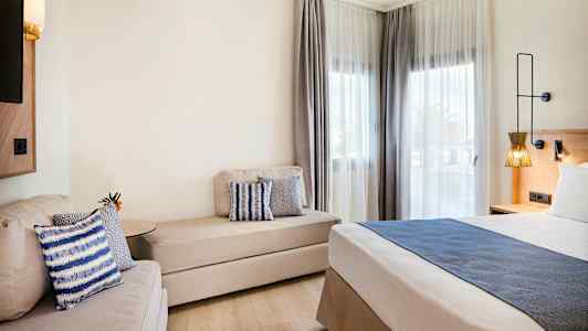 Modernt hotellrum med säng, soffa och fönster med ljusa gardiner. (AI-genererad text)