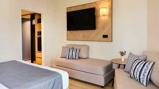 Ett hotellrum med soffa, säng och TV på väggen. (AI-genererad text)