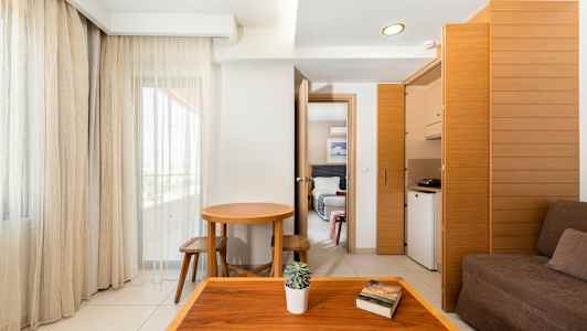 Ett hotellrum med enkel inredning, mörka möbler och stora fönster. (AI-genererad text)