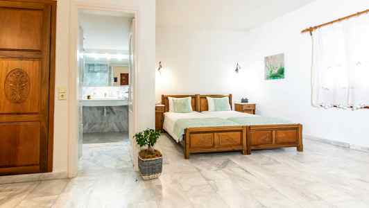 Ett sovrum med två enkelsängar och en dörr som leder till ett badrum. (AI-genererad text)