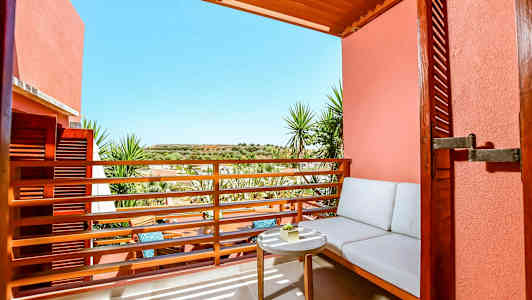 Uteplats med sittplats och bord mot solig utsikt. (AI-genererad text)