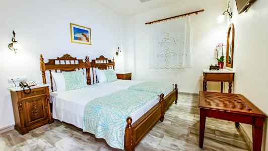 Ett sovrum med två enkelsängar, träinredning och dekorerade sänggavlar. (AI-genererad text)