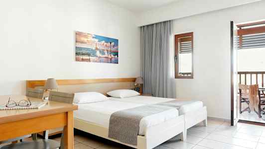 Hotellrum med två enkelsängar, ett träbord och stol samt balkong. (AI-genererad text)