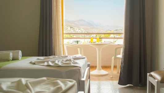 Ett hotellrum med två bäddar och en möblerad balkong med utsikt. (AI-genererad text)