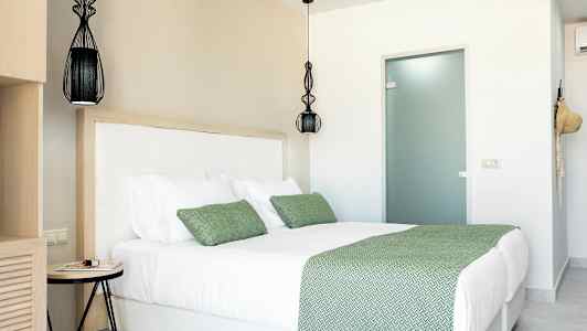 Ett rum med en dubbelsäng med gröna sängkläder och kuddar. (AI-genererad text)