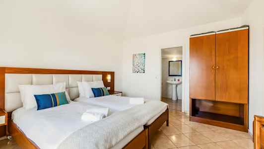 Ett hotellrum med två bäddade sängar, en garderob och ingång till ett badrum. (AI-genererad text)