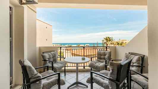 Terrass med fyra sittplatser kring ett bord, havsutsikt i bakgrunden. (AI-genererad text)