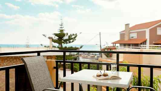 En balkong med ett bord, en stol och utsikt mot havet. (AI-genererad text)