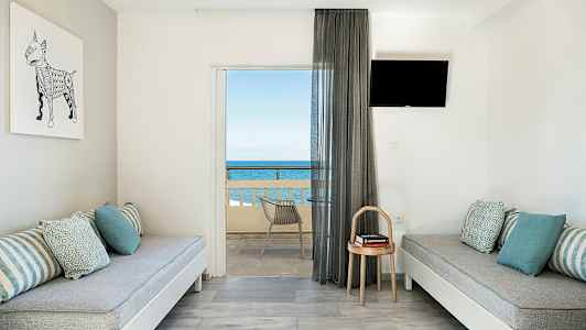 Modernt inrett rum med två bänkar, kuddar, en liten bord och en balkong med havsutsikt. (AI-genererad text)