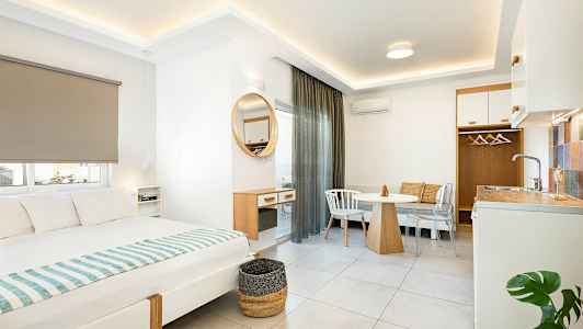 Interiör av ett modernt hotellrum med säng, matbord och liten köksdel. (AI-genererad text)