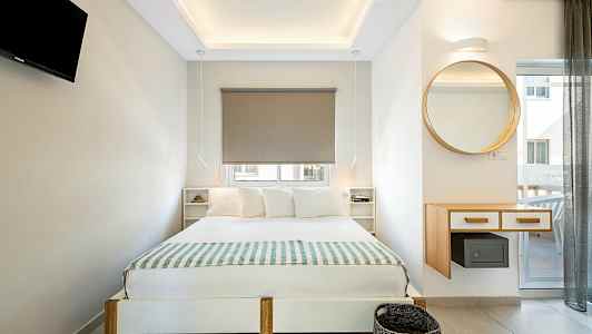 Modernt inrett sovrum med dubbelsäng, vägghängd TV och en rund spegel. (AI-genererad text)