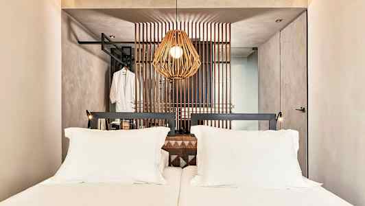 En hotellrum med en dubbelsäng och en dekorativ träpanel bakom sängen. (AI-genererad text)