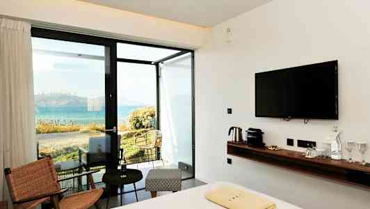 Ett hotellrum med modern inredning och utsikt över havet. (AI-genererad text)