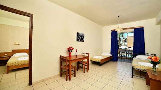 Ett hotellrum med tre sängar, matbord och stor fönsterutgång. (AI-genererad text)