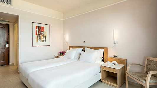 Ett hotellrum med en dubbelsäng, sängbord och stol. (AI-genererad text)